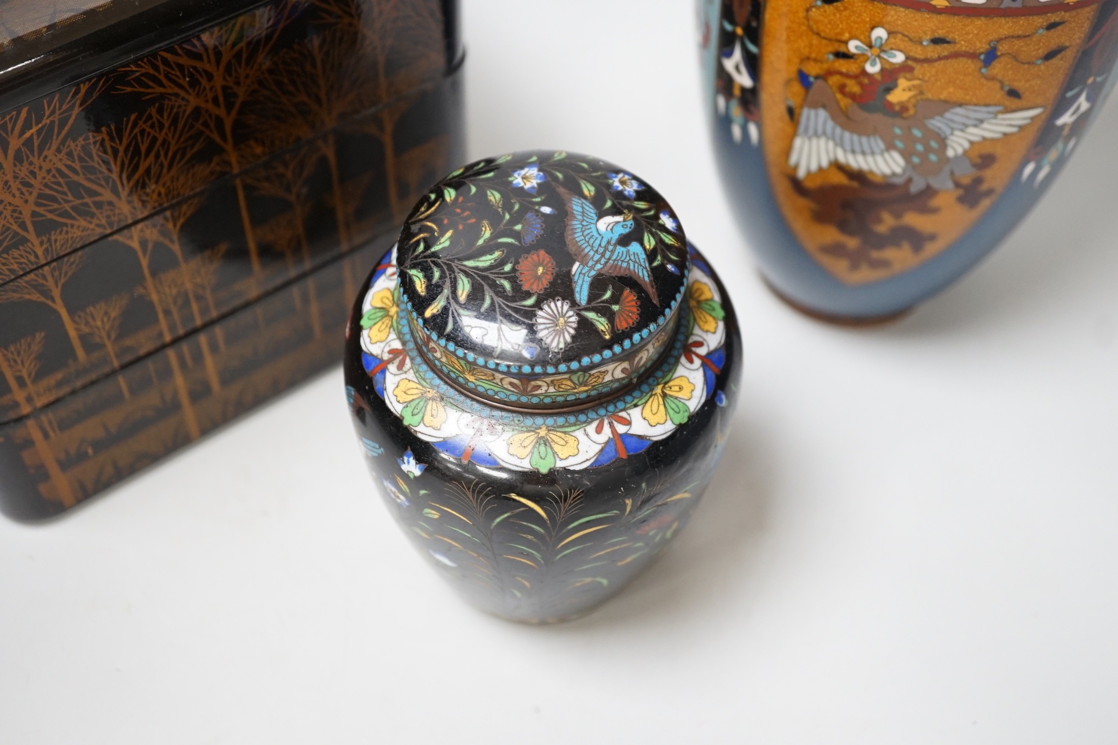 A large Japanese cloisonné enamel vase, 30.5cm high, a similar jar and cover and a Japanese lacquered tiered box with 3-4 drawers. Tree design in gold lacquer.